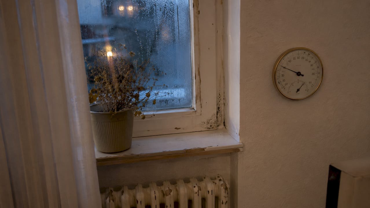 Måling af luftfugtighed ved vindue med hygrometer og tegn på kondens i vindueskarmen