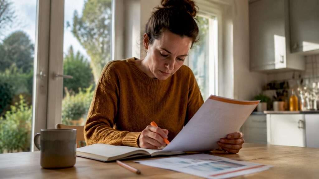 En kvinde sidder hjemme på kontoret og gennemgår sin forsikringsaftale.